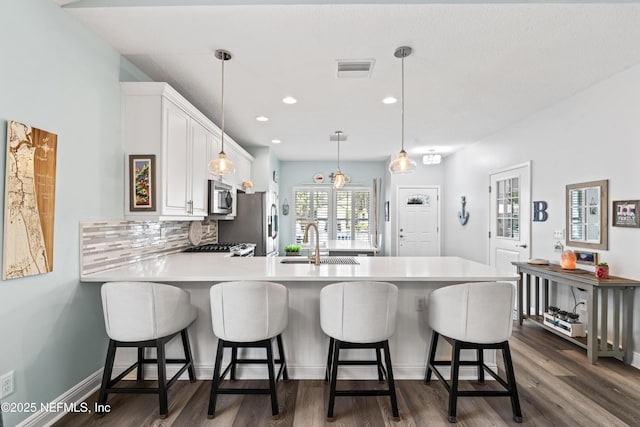 kitchen featuring a peninsula, a sink, white cabinets, light countertops, and appliances with stainless steel finishes