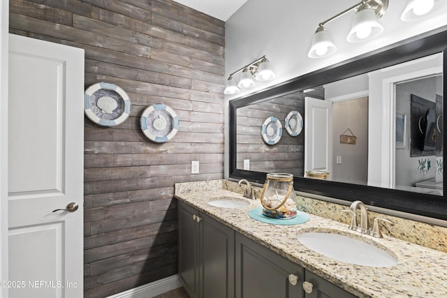 bathroom featuring double vanity, a sink, and wooden walls