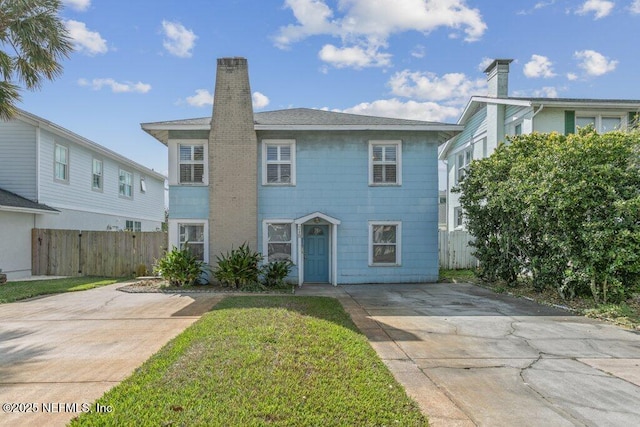 view of front of house featuring a front lawn, a chimney, and fence