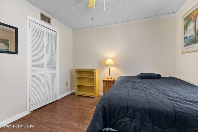 bedroom with crown molding, a closet, visible vents, a textured ceiling, and wood finished floors