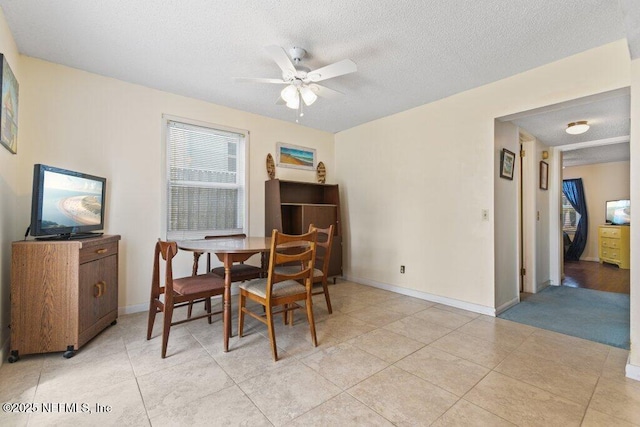 dining room with light tile patterned floors, ceiling fan, baseboards, and a textured ceiling