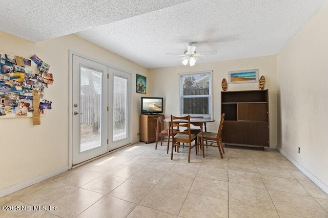 dining space featuring light tile patterned floors, ceiling fan, baseboards, and a textured ceiling