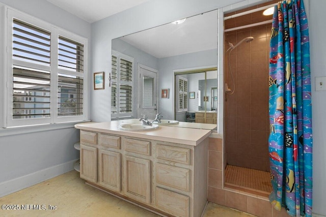 full bath with a stall shower, vanity, and baseboards