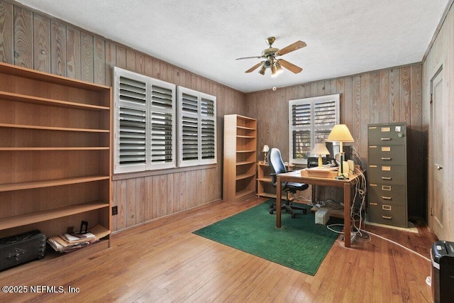 office featuring light wood-type flooring, ceiling fan, and wooden walls