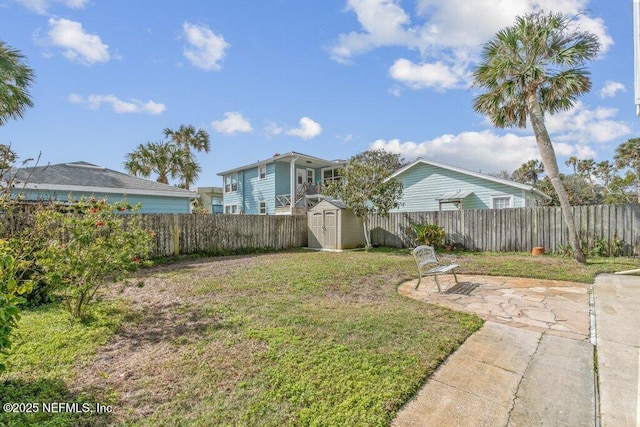 view of yard featuring an outbuilding, a patio area, a fenced backyard, and a storage unit