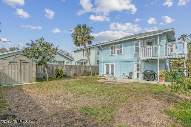 rear view of house with an outbuilding, fence, a yard, a storage unit, and a patio area