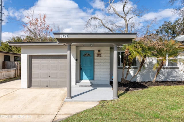 view of front facade with a garage, brick siding, fence, driveway, and a front lawn