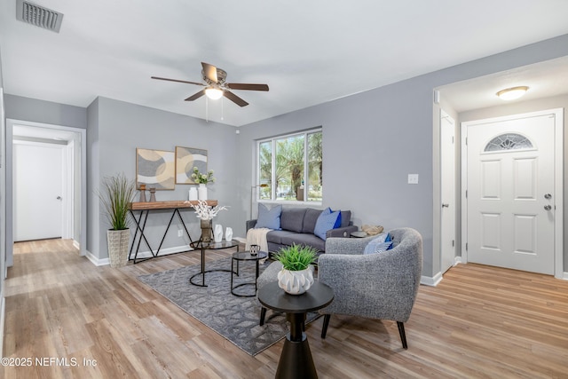 living area with light wood-style flooring, visible vents, ceiling fan, and baseboards