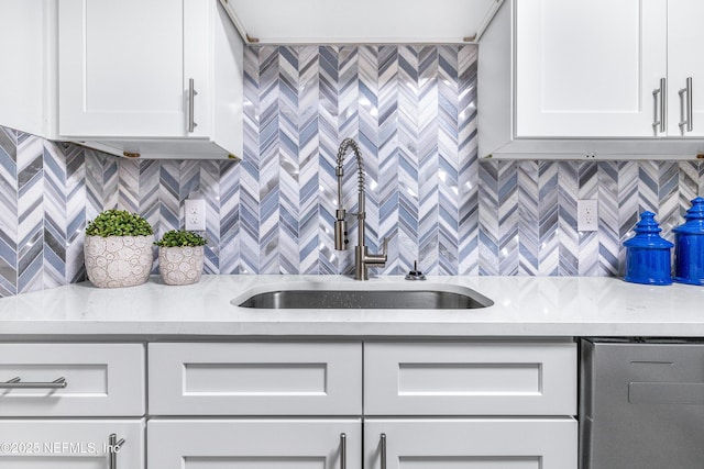 kitchen featuring light stone counters, a sink, white cabinetry, and tasteful backsplash