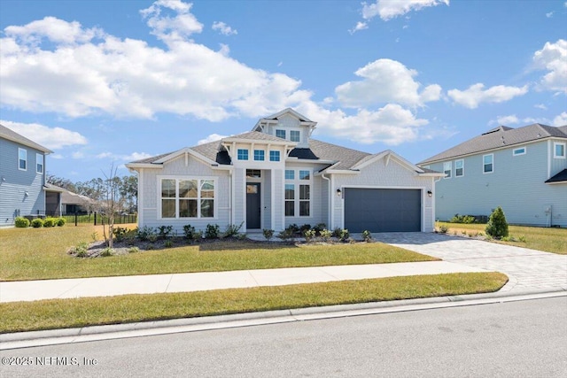 view of front of property with a garage, decorative driveway, and a front yard