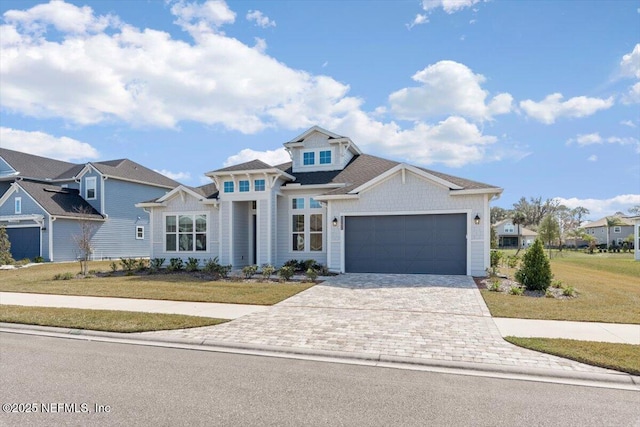 view of front of home featuring an attached garage, a front lawn, and decorative driveway