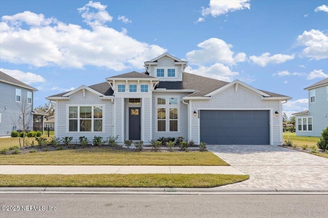 view of front of home with a front yard, decorative driveway, and an attached garage