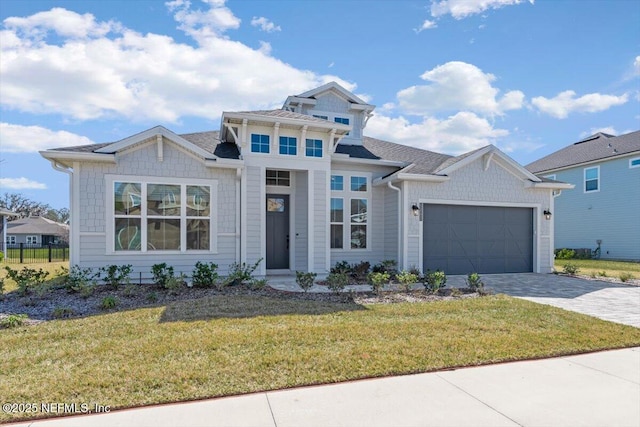 view of front of property with a garage, a front lawn, and decorative driveway