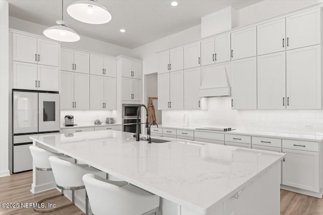 kitchen featuring appliances with stainless steel finishes, decorative backsplash, white cabinetry, and custom range hood