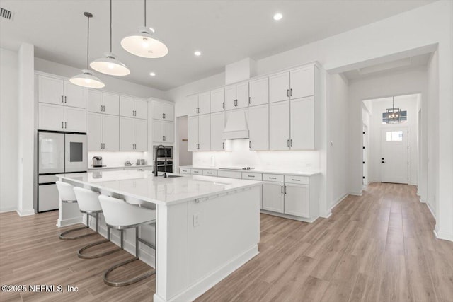 kitchen featuring fridge, custom range hood, and white cabinets