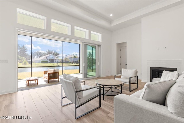 living area featuring light wood finished floors, a brick fireplace, and a high ceiling