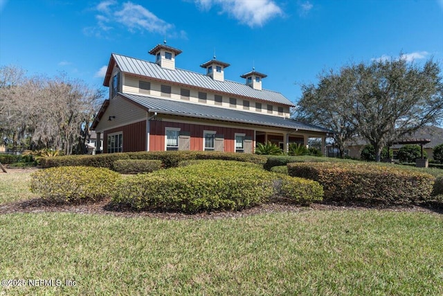 rear view of house with a standing seam roof, metal roof, a chimney, and a lawn