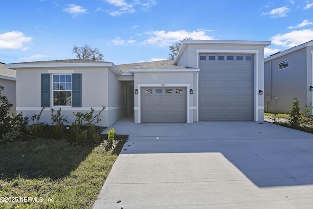 view of front of house with concrete driveway, an attached garage, and stucco siding