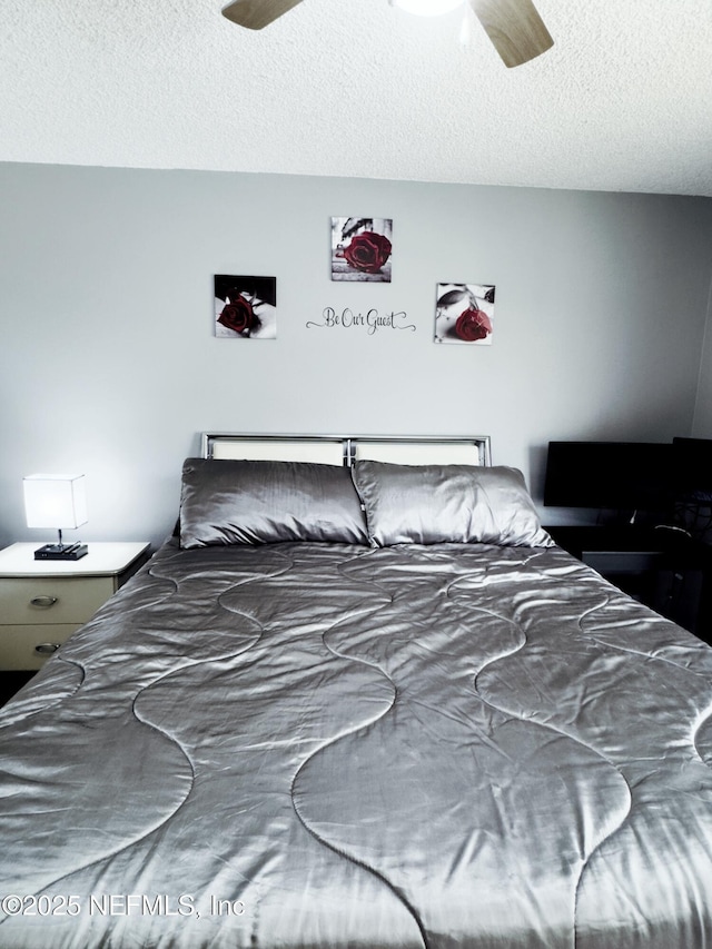 bedroom with ceiling fan and a textured ceiling