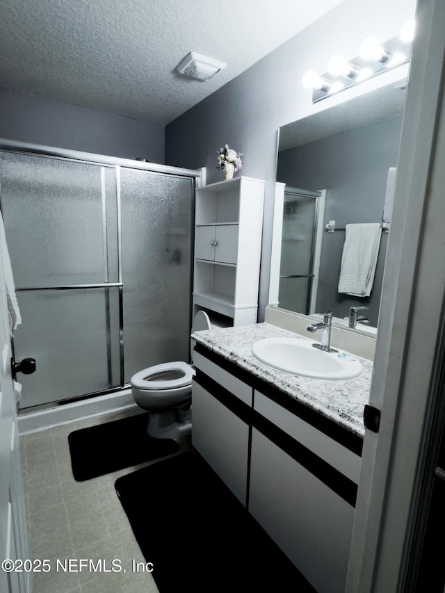 bathroom with visible vents, toilet, a textured ceiling, vanity, and a shower stall