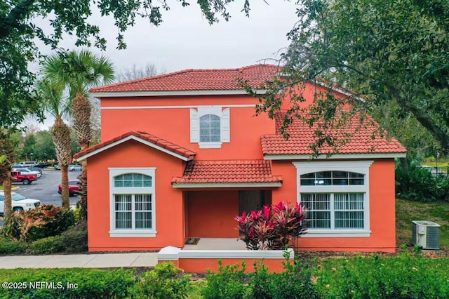 rear view of house featuring a tiled roof and stucco siding