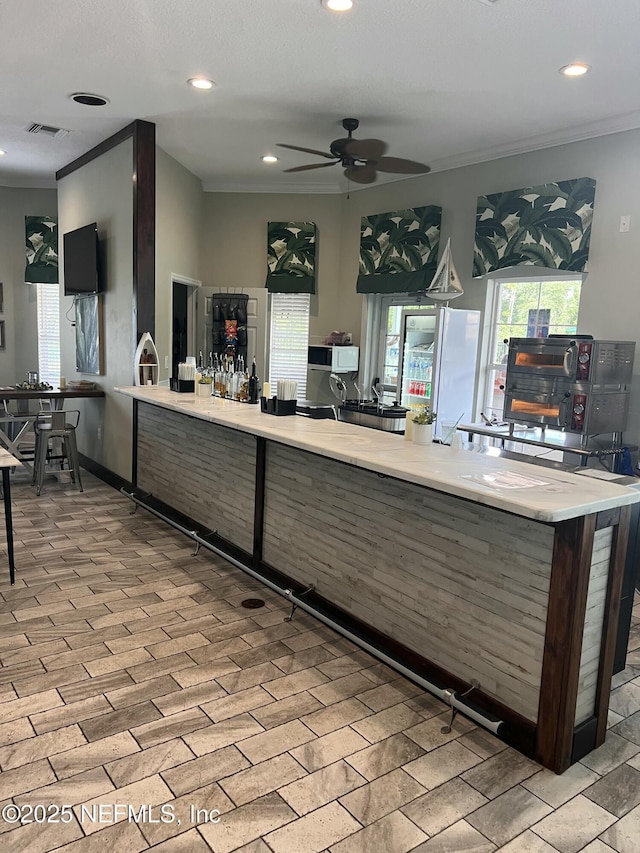 interior space with ornamental molding, recessed lighting, light countertops, and visible vents