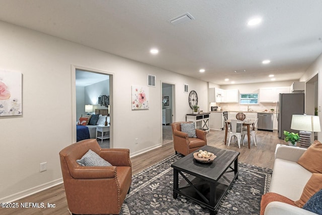 living room with visible vents, wood finished floors, and recessed lighting