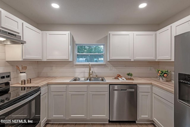 kitchen with light countertops, appliances with stainless steel finishes, a sink, and white cabinets