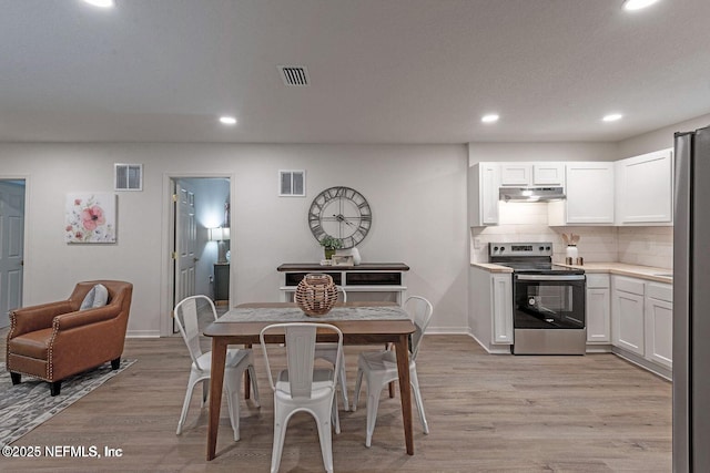 dining space with light wood-type flooring, visible vents, and recessed lighting