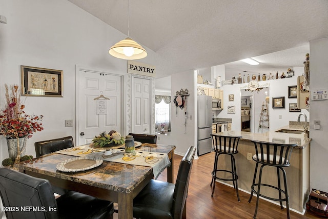 dining area featuring dark wood-style floors, lofted ceiling, and a textured ceiling