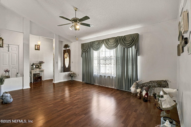 interior space with vaulted ceiling, a textured ceiling, wood finished floors, and a ceiling fan