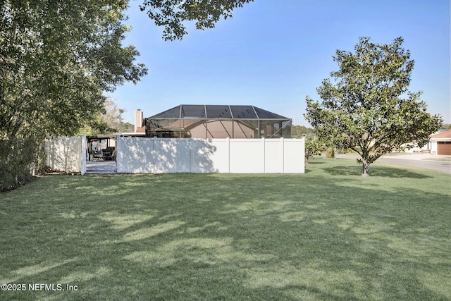 view of yard with glass enclosure and fence