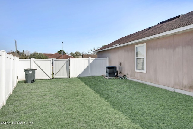 view of yard featuring central air condition unit, a fenced backyard, and a gate