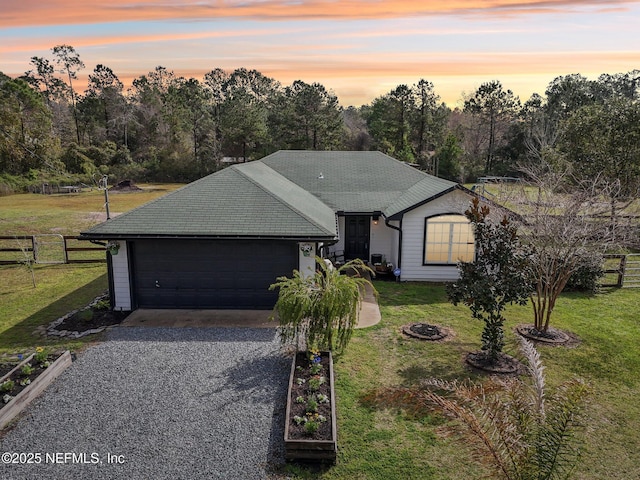 ranch-style home with a front lawn, fence, and driveway