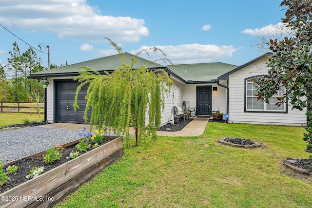 rear view of property featuring a garage, a lawn, a vegetable garden, and driveway