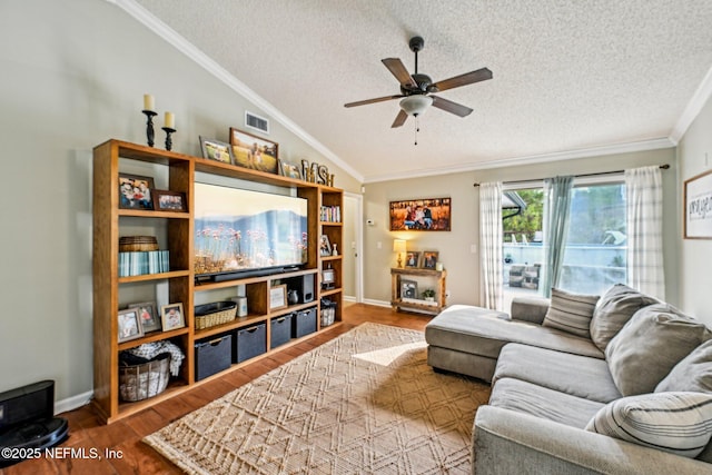 living area featuring visible vents, ornamental molding, a ceiling fan, wood finished floors, and vaulted ceiling