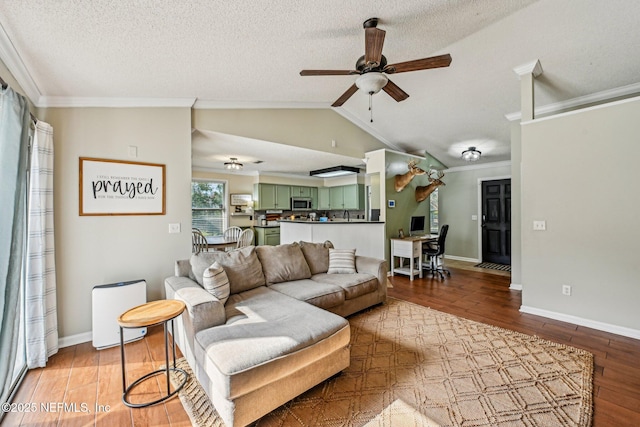 living room featuring ceiling fan, lofted ceiling, ornamental molding, light wood-style flooring, and a textured ceiling