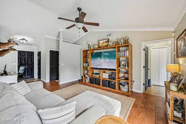 living area with visible vents, wood finished floors, crown molding, and vaulted ceiling