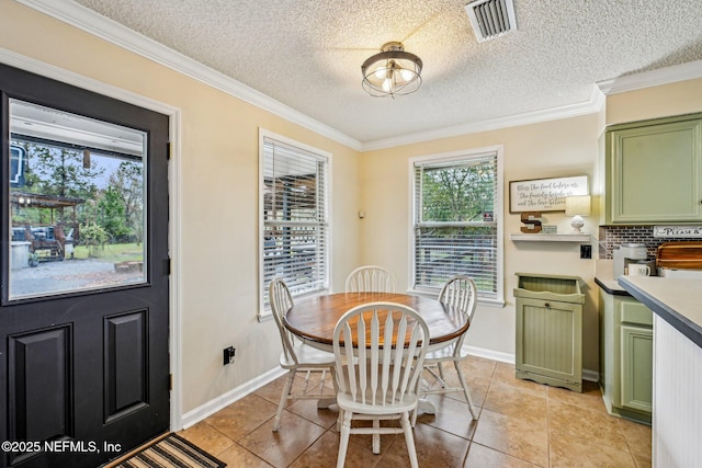 dining space with visible vents, ornamental molding, a textured ceiling, light tile patterned flooring, and baseboards