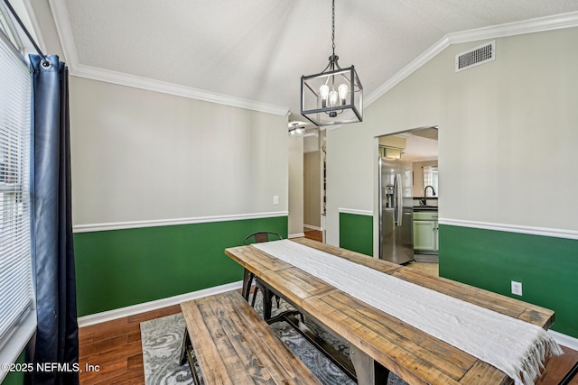 dining room featuring visible vents, lofted ceiling, wood finished floors, and crown molding