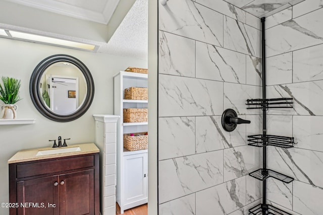 bathroom with a tile shower and vanity