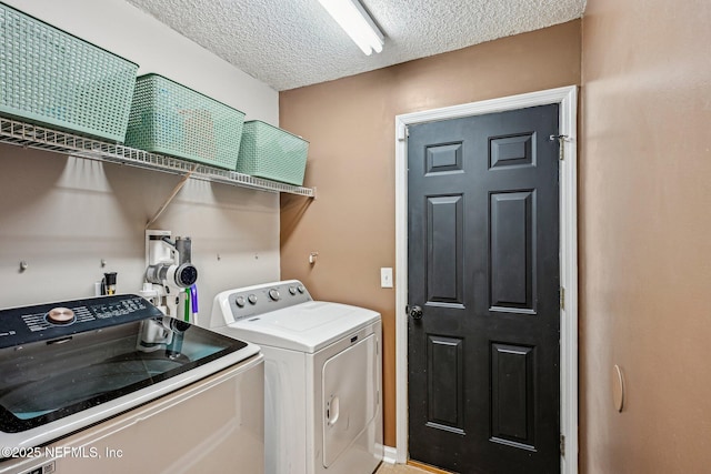 clothes washing area featuring washing machine and clothes dryer, laundry area, and a textured ceiling