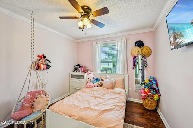 bedroom featuring a textured ceiling, wood finished floors, baseboards, and ornamental molding