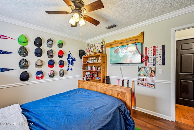 bedroom with visible vents, a textured ceiling, wood finished floors, and crown molding