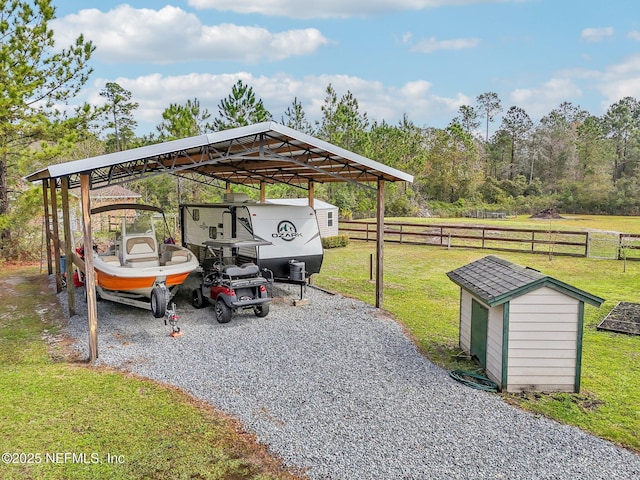 view of parking / parking lot featuring a detached carport, gravel driveway, and fence