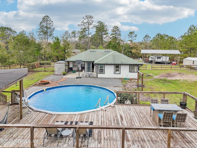 outdoor pool with a deck, a lawn, and fence