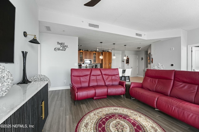 living room with visible vents, dark wood finished floors, and a textured ceiling