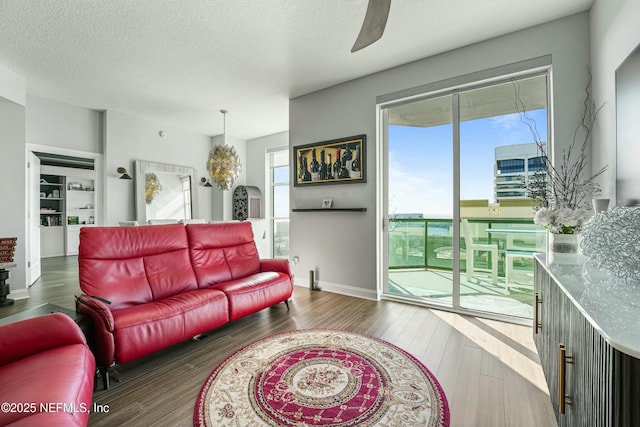 living room featuring a textured ceiling, ceiling fan, dark wood-type flooring, and baseboards