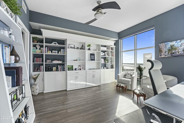 living area with a textured ceiling, ceiling fan, and dark wood-type flooring