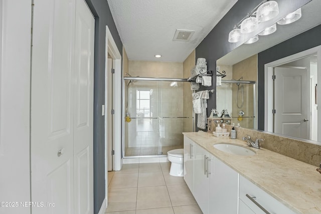 bathroom featuring a closet, visible vents, toilet, a textured ceiling, and tile patterned floors